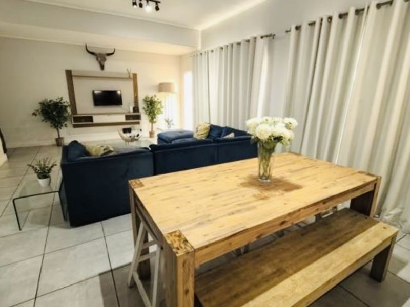 Spacious open-plan living and dining area featuring neutral tiled flooring, recessed lighting, and a modern built-in media console.