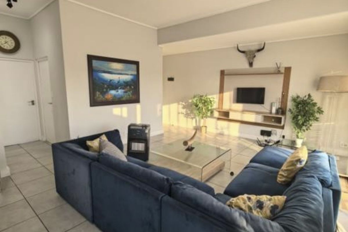 Spacious living room featuring neutral tiled flooring, modern recessed track lighting, and a built-in media console unit.