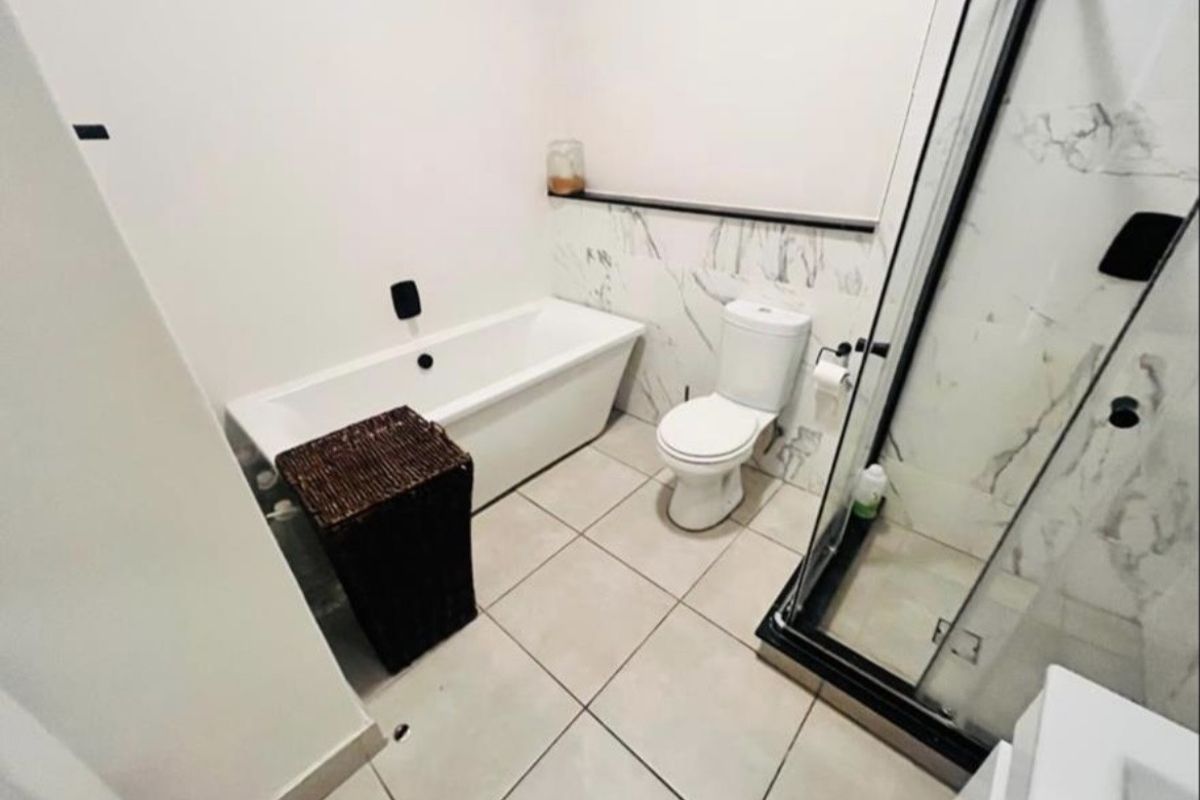 Modern bathroom featuring a bathtub, separate shower enclosure, toilet, and elegant marble-look wall tiling.
