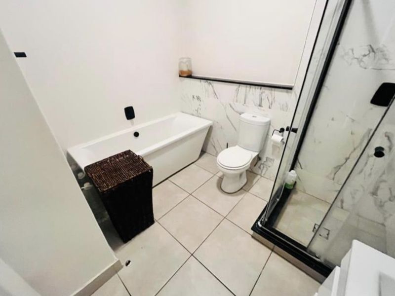 Modern bathroom featuring a bathtub, separate shower enclosure, toilet, and elegant marble-look wall tiling.