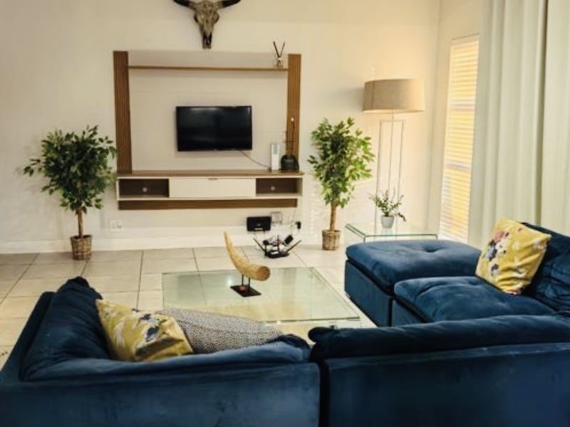 A well-maintained living room featuring tiled flooring, a built-in media console, and recessed ceiling lighting, creating a comfortable and functional space.