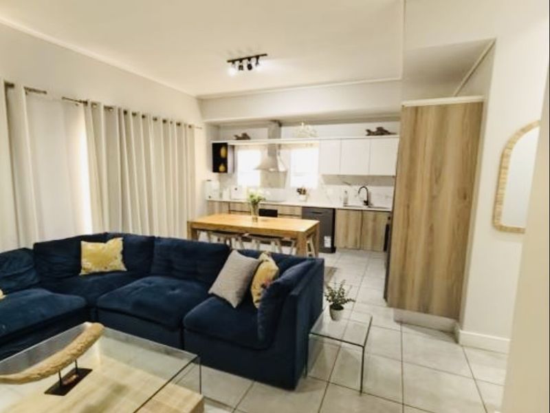 An open-plan living and kitchen area featuring tiled flooring, modern cabinetry, and a functional layout suitable for contemporary apartment living.