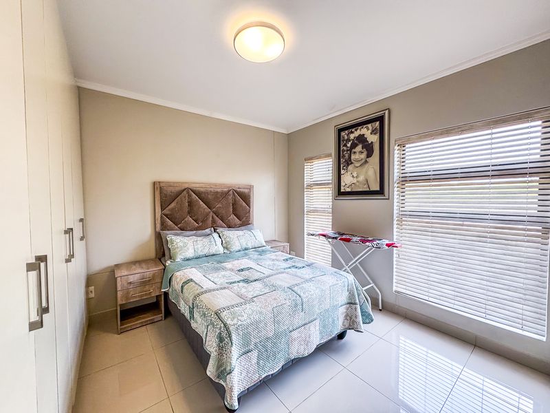 A well-maintained bedroom featuring neutral tiled flooring, built-in cupboards for storage, and venetian blinds allowing for natural light control.