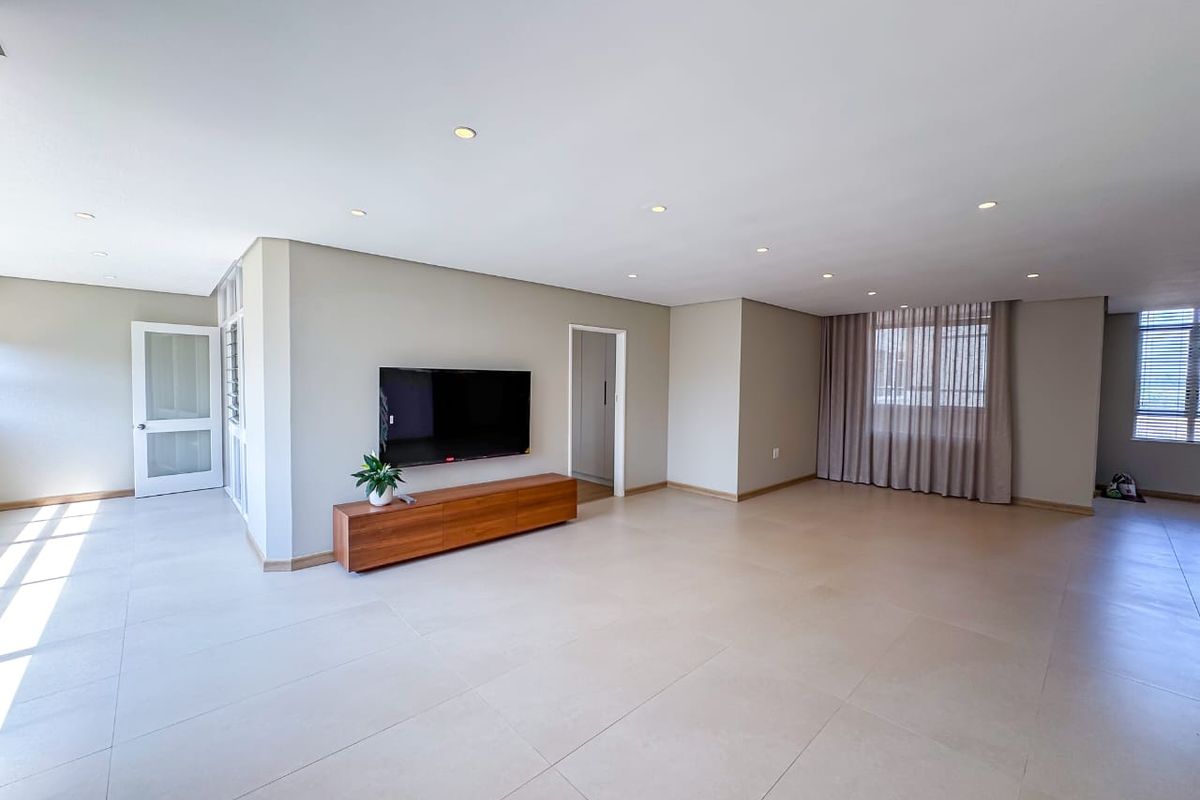 Spacious and bright open-plan living area featuring neutral tiled flooring, recessed downlighting, and clean finishes throughout.
