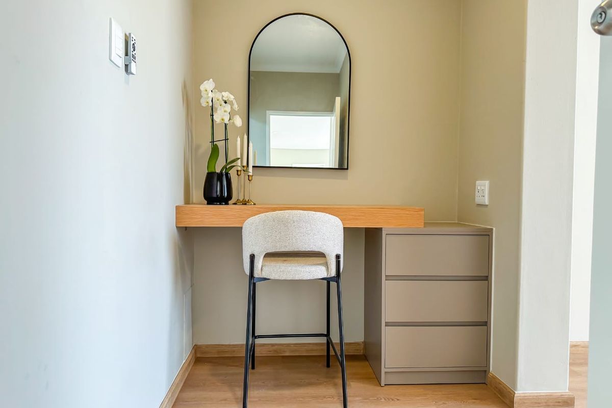 A compact bedroom nook featuring a modern built-in floating desk, integrated drawer storage, and light wood-look laminate flooring.