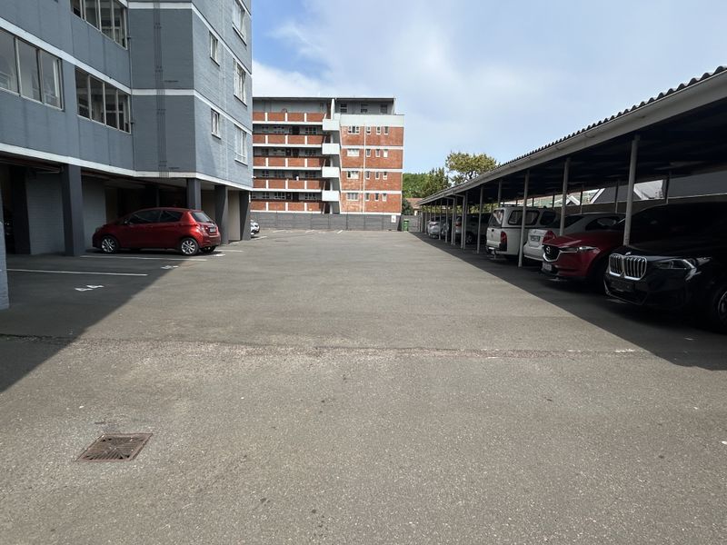 Outdoor parking area featuring covered parking bays with asphalt surfacing and drainage infrastructure.