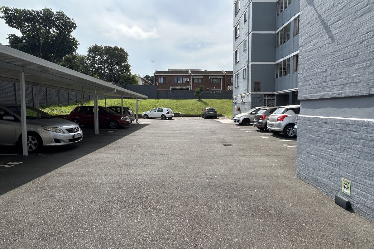 Exterior view of the apartment complex parking area featuring covered parking bays and a paved driveway.