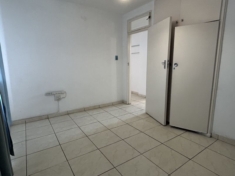 An empty bedroom featuring tiled flooring and built-in cupboards, offering a blank canvas for personalization.