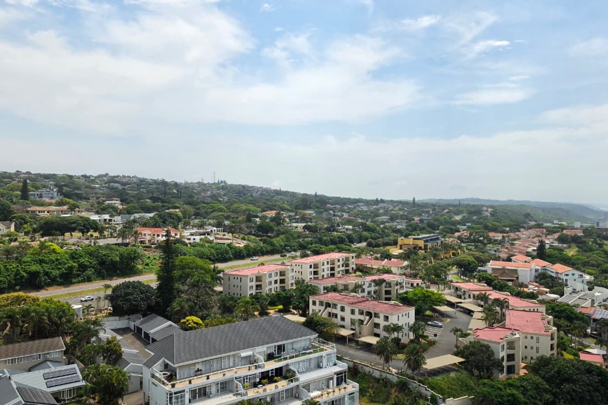An elevated aerial view showcasing the surrounding residential neighborhood, apartment complexes, and lush green landscape.