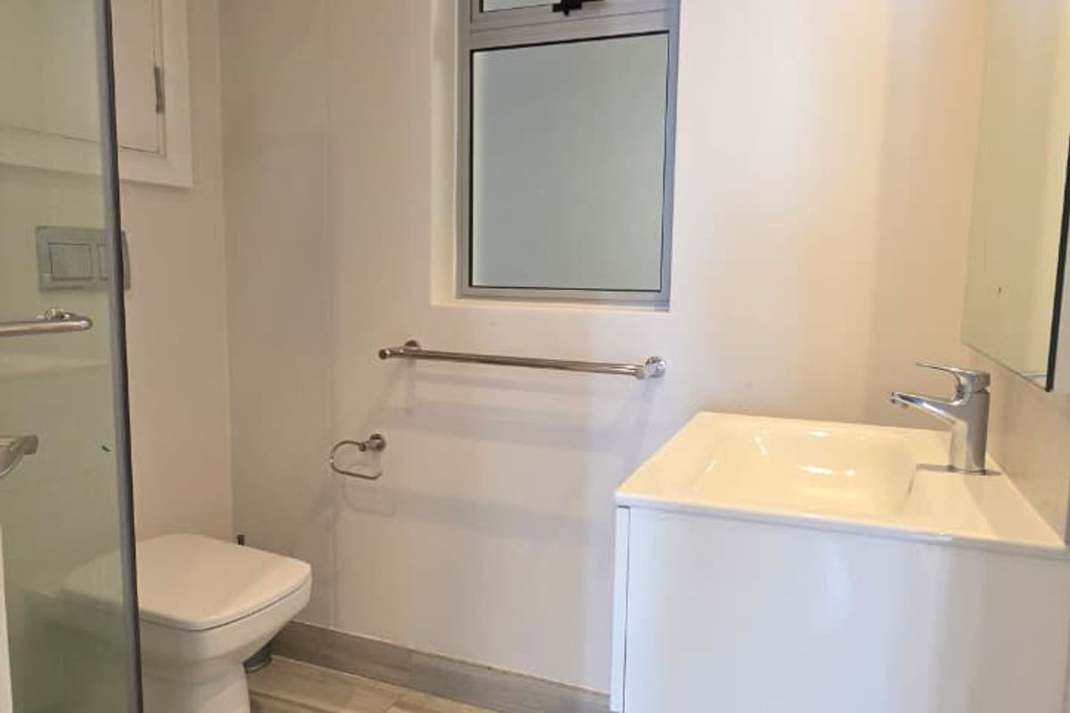 A clean, modern bathroom featuring a glass shower enclosure, wall-mounted toilet, and a sleek vanity unit with a basin.