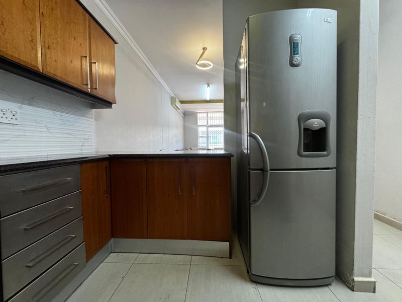 A functional kitchen area featuring wooden cabinetry, granite countertops, and tiled flooring, providing a practical layout for daily meal preparation.