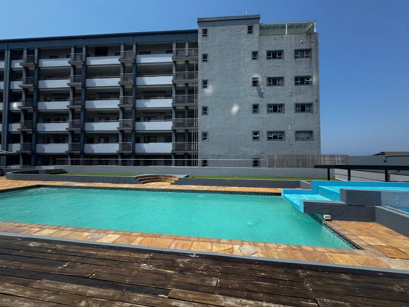Communal swimming pool area featuring a paved deck and views of the multi-story apartment building facade.