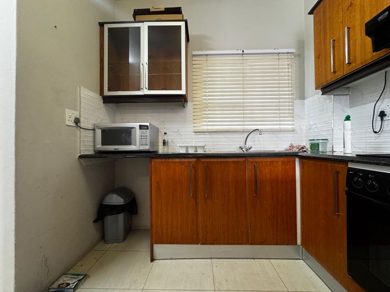 A functional kitchen featuring wooden cabinetry, granite countertops, a built-in oven, and tiled backsplash, offering a practical layout for daily meal preparation.