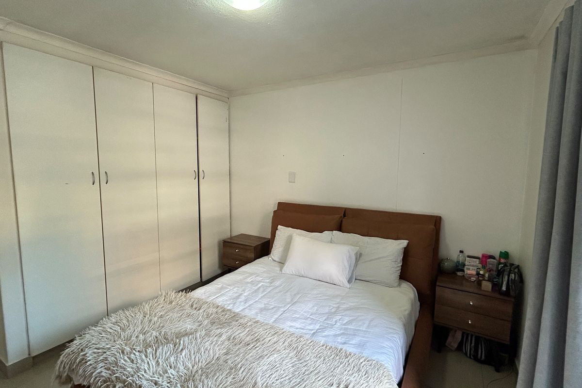 A functional bedroom featuring floor-to-ceiling built-in cupboards and neutral wall finishes, providing a clean and practical space.