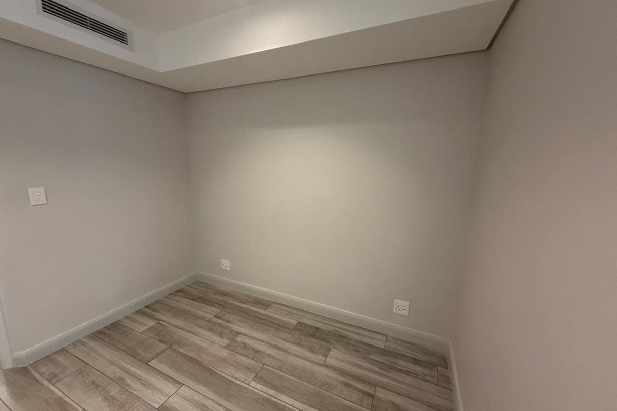 A clean, empty bedroom featuring modern wood-look tile flooring and integrated ducted air conditioning, providing a neutral canvas for personalization.