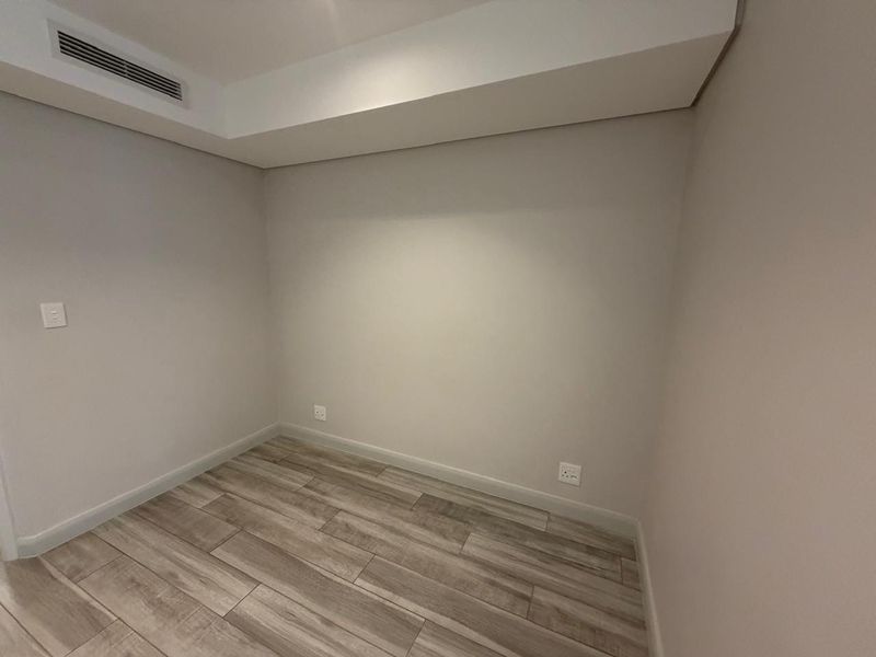 A clean, empty bedroom featuring modern wood-look tile flooring and integrated ducted air conditioning, providing a neutral canvas for personalization.