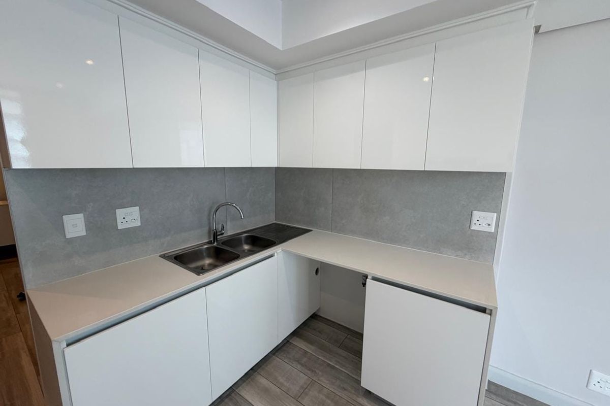Modern kitchen featuring white gloss cabinetry, stone countertops, a double stainless steel sink, and a sleek grey tiled backsplash.