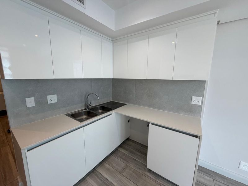 Modern kitchen featuring white gloss cabinetry, stone countertops, a double stainless steel sink, and a sleek grey tiled backsplash.