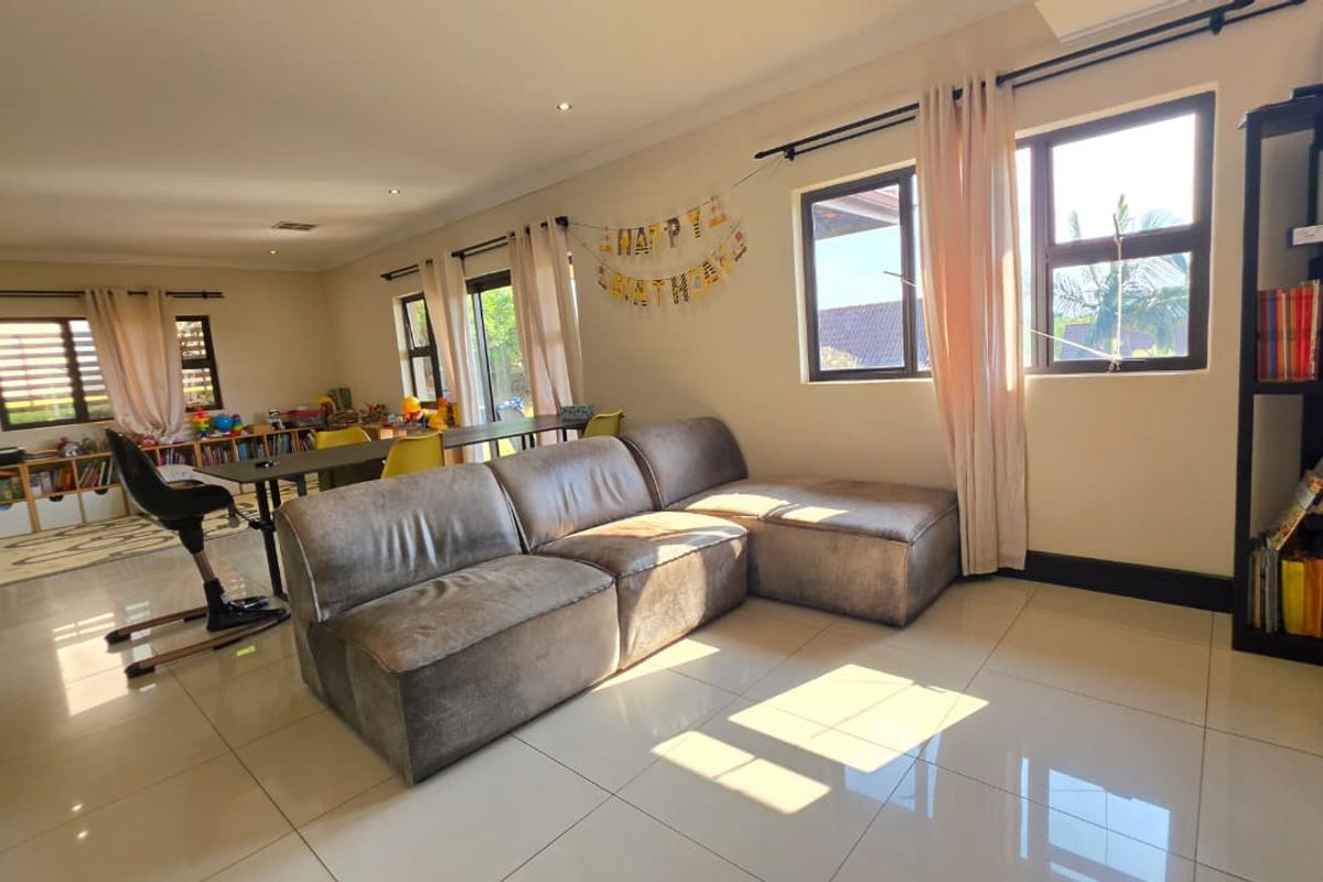 Spacious living area featuring large windows, tiled flooring, and recessed lighting, offering a bright and versatile space for family relaxation.