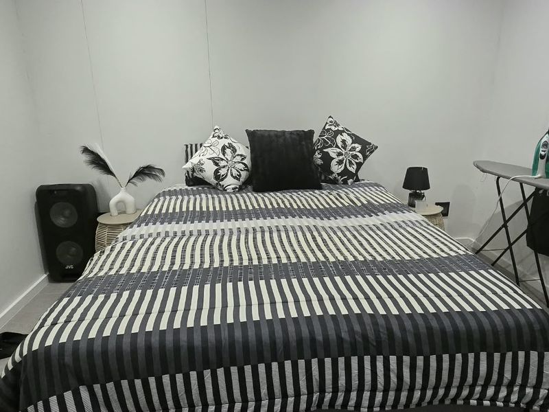 A compact bedroom featuring tiled flooring and a window with dark curtains, providing a functional space for rest.