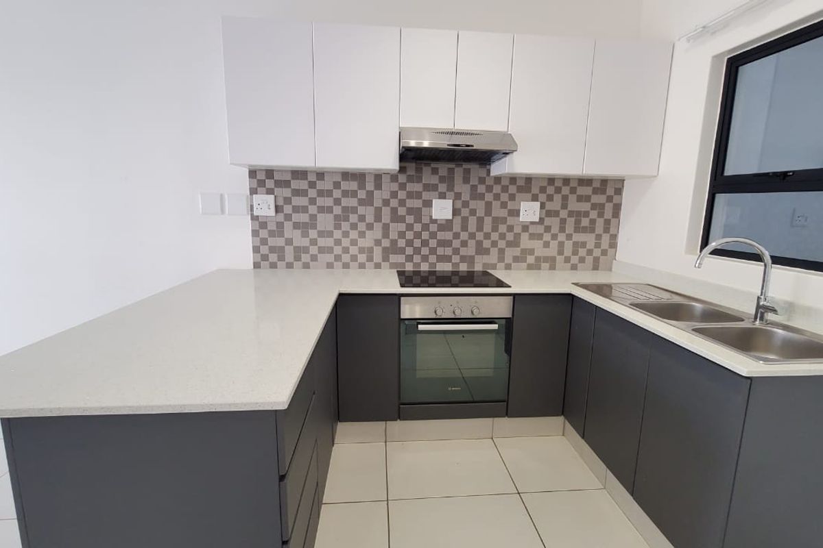 Modern kitchen featuring sleek two-tone cabinetry, quartz countertops, mosaic backsplash, and integrated stainless steel appliances, offering a clean and functional culinary space.