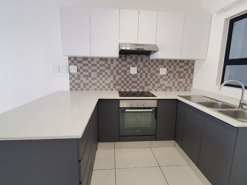 Modern kitchen featuring sleek two-tone cabinetry, quartz countertops, mosaic backsplash, and integrated stainless steel appliances, offering a clean and functional culinary space.