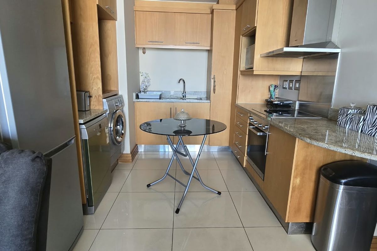 Compact kitchen featuring light wood cabinetry, granite countertops, integrated appliances, and tiled flooring, offering a functional and efficient workspace.