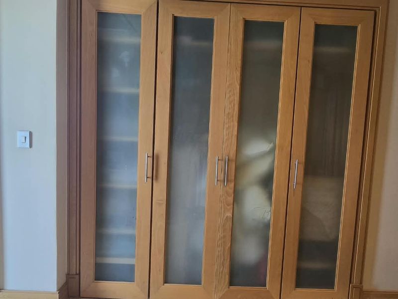 Bedroom featuring a large built-in wooden wardrobe with frosted glass panels, providing ample storage space within the room.