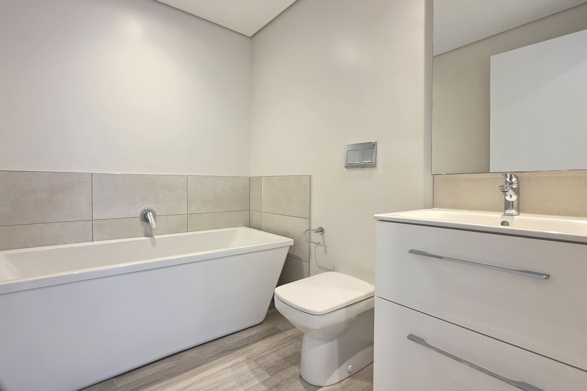 Modern bathroom featuring a sleek freestanding bathtub, wall-hung toilet with concealed cistern, and a contemporary vanity unit with integrated basin.