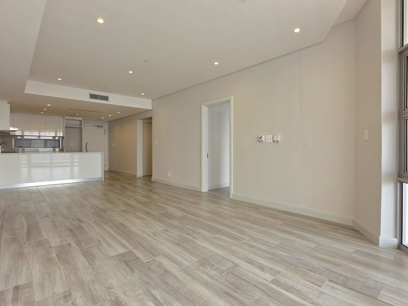 Spacious open-plan living area featuring modern tiled flooring, recessed lighting, ducted air conditioning, and a sleek integrated kitchen with a breakfast island.