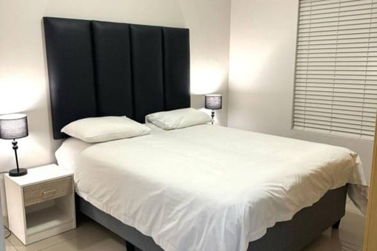 A well-maintained bedroom featuring neutral tiled flooring, crown molding, and venetian blinds, providing a clean and comfortable living space.
