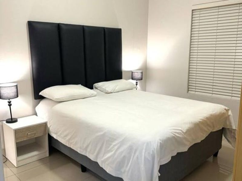 A well-maintained bedroom featuring neutral tiled flooring, crown molding, and venetian blinds, providing a clean and comfortable living space.