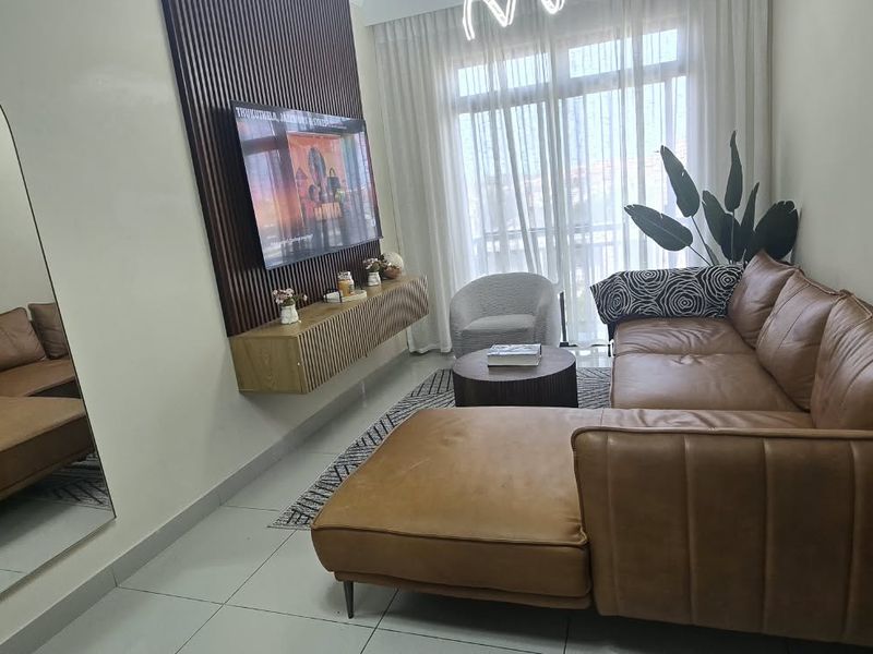 A modern living room featuring a stylish slatted timber accent wall, tiled flooring, and large floor-to-ceiling mirror, creating a bright and contemporary living space.