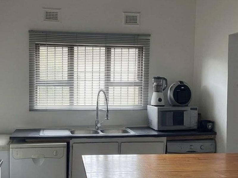A functional kitchen area featuring a double sink, tiled flooring, and built-in cabinetry, offering a practical layout ready for modernization.