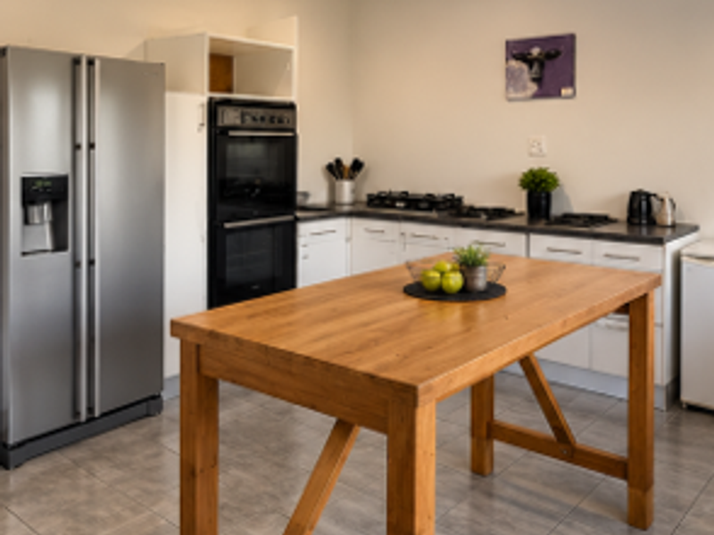 A functional kitchen featuring a built-in double oven, gas hob, laminate countertops, and tiled flooring, providing a practical workspace.