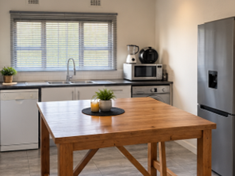 A functional kitchen featuring tiled flooring, built-in cabinetry, a double sink with mixer tap, and venetian blinds.