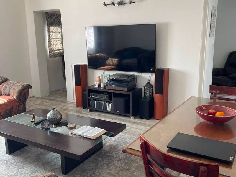 An open-plan living and dining area featuring tiled flooring, neutral walls, and integrated lighting fixtures, providing a functional and versatile living space.