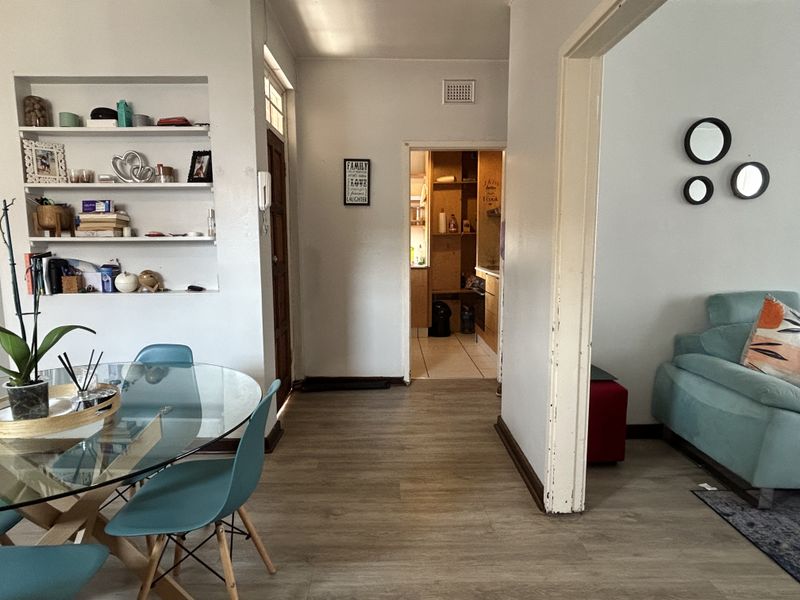 Open plan living area featuring laminate flooring, a built-in wall niche for storage, and an archway leading to the kitchen area.