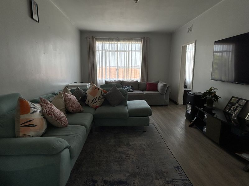 A spacious living room featuring laminate flooring and a large window that allows for natural light, providing a comfortable and functional living space.