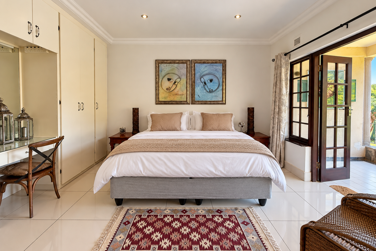 A well-maintained bedroom featuring built-in cupboards, tiled flooring, and direct access to an outdoor patio through classic french doors.