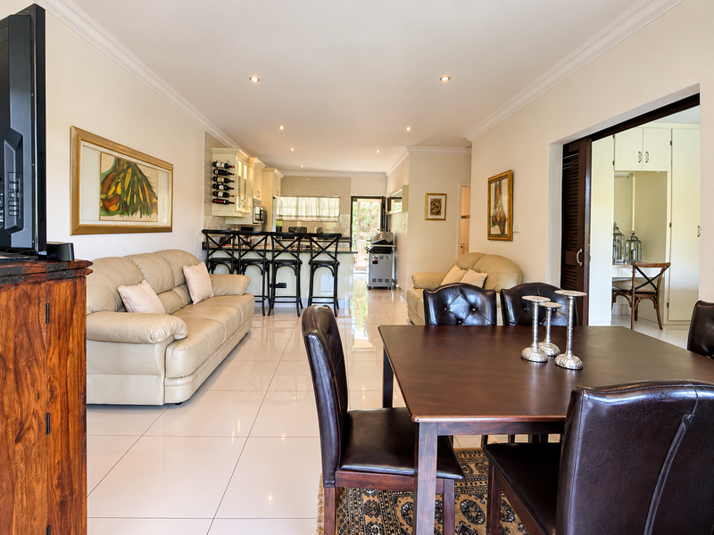 Spacious open-plan living and dining area featuring polished porcelain floor tiles, recessed lighting, and a modern kitchen with a breakfast bar.