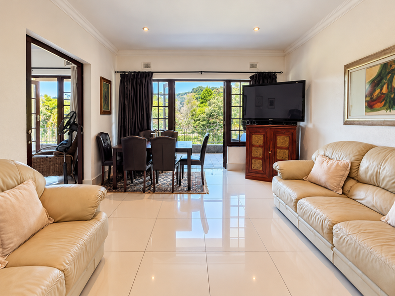 Spacious open-plan living and dining area featuring polished porcelain floor tiles, recessed lighting, and direct access to a private balcony with scenic views.