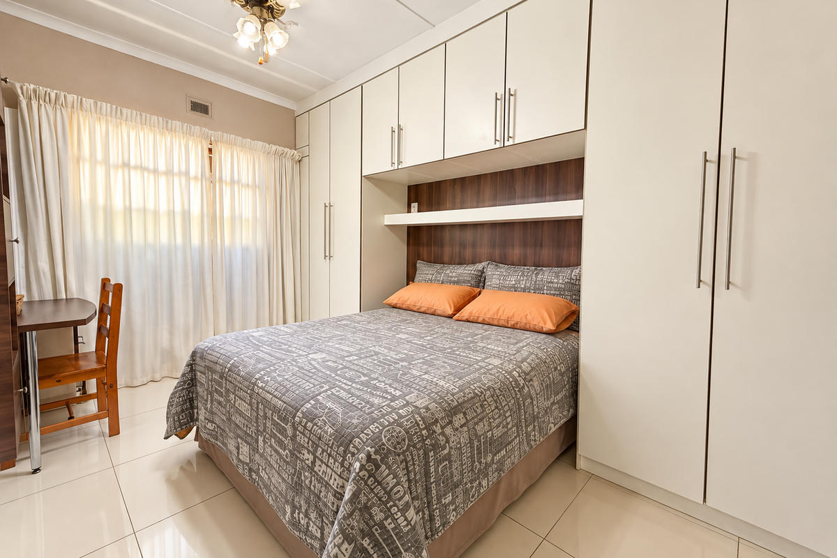 A well-maintained bedroom featuring extensive built-in cabinetry, integrated headboard shelving, a ceiling fan, and neutral tiled flooring.