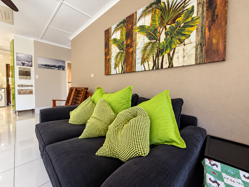 A well-maintained living area featuring polished tiled flooring, neutral wall tones, and a ceiling fan, providing a comfortable and bright space.