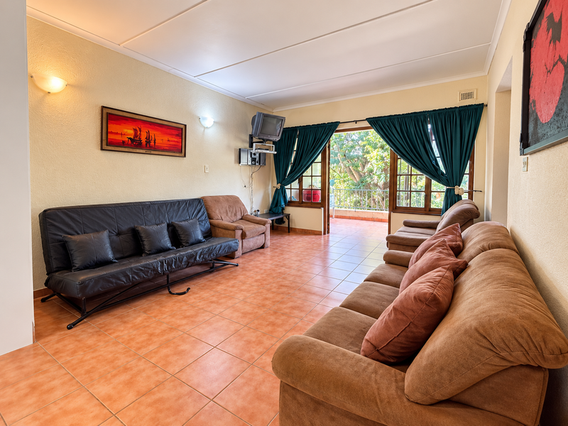 Spacious living room featuring tiled flooring and direct access to an outdoor balcony through sliding glass doors, offering a bright and functional layout.