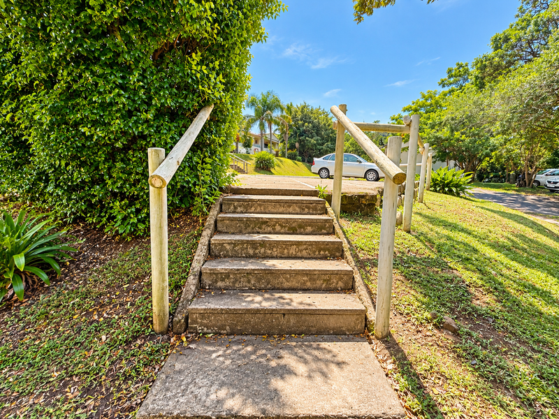 Exterior concrete staircase with timber handrails providing access through a landscaped garden area.