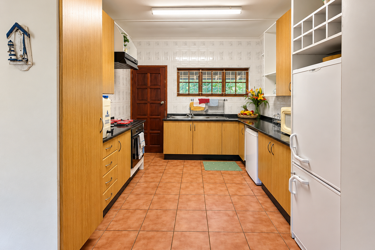 A functional kitchen featuring laminate cabinetry, dark countertops, a built-in oven with hob, and tiled flooring throughout.