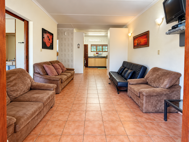 Open plan living area featuring tiled flooring and a direct view into the kitchen space with built-in cabinetry.