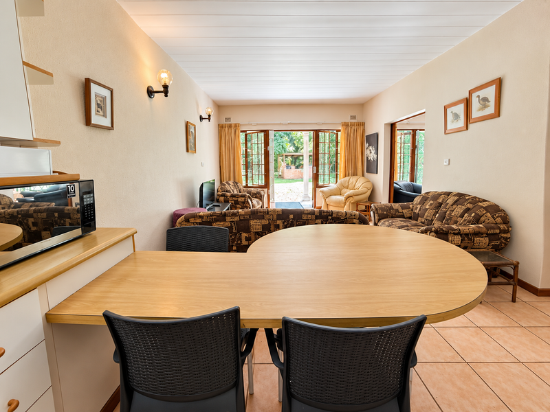 Open-plan living and dining area featuring tiled floors, built-in kitchen cabinetry, and direct access to an outdoor patio through double glass doors.