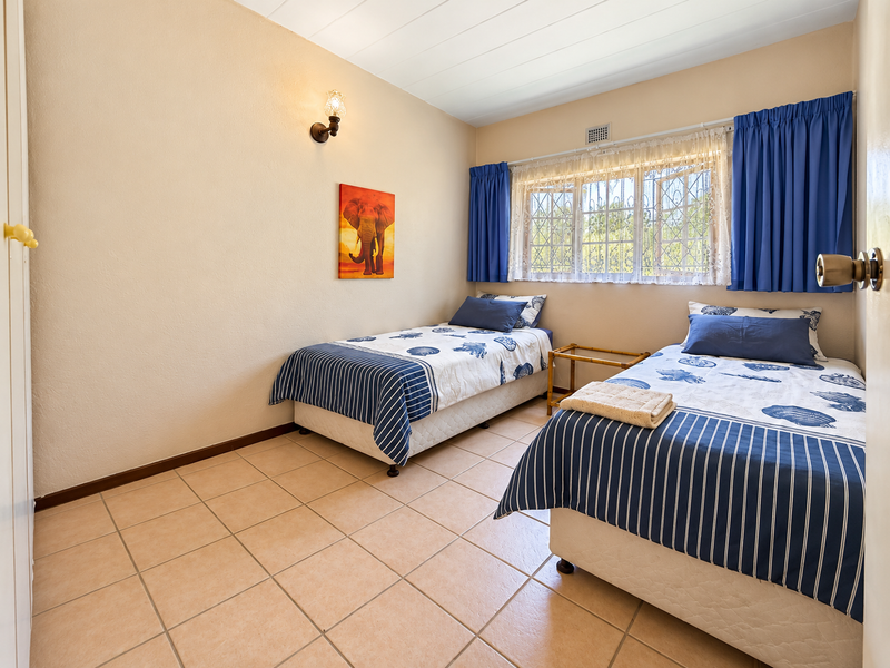 A functional bedroom featuring tiled flooring, built-in storage, and a window with security bars, offering a clean and well-maintained living space.